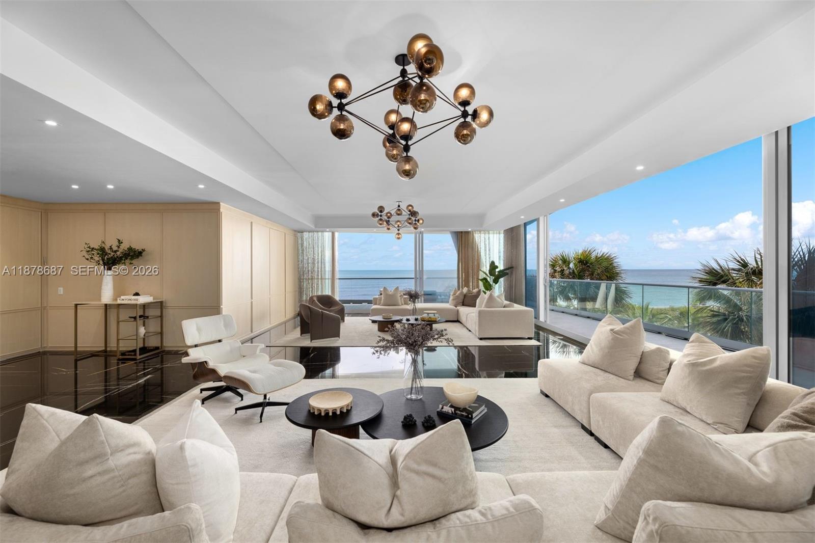 A spacious living room features modern chandeliers, white sofas, and floor-to-ceiling windows overlooking the ocean — 9349 Collins Ave # 406, Surfside FL 33154, SURFSIDE, FL