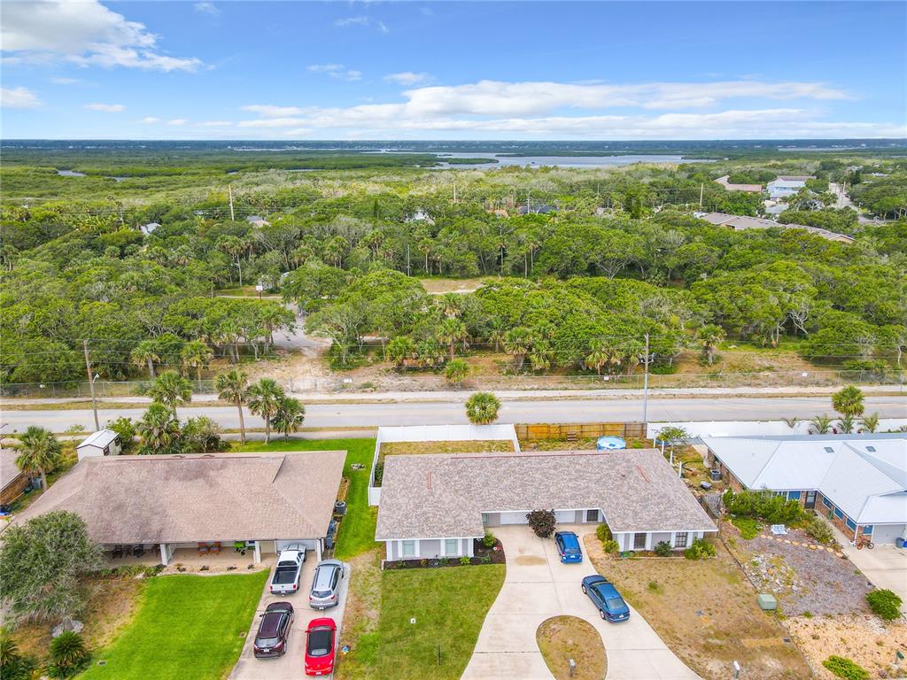 An aerial view shows two adjacent houses with driveways and a large wooded area behind — 3828 SANDSTONE COURT, NEW SMYRNA BEACH, FL