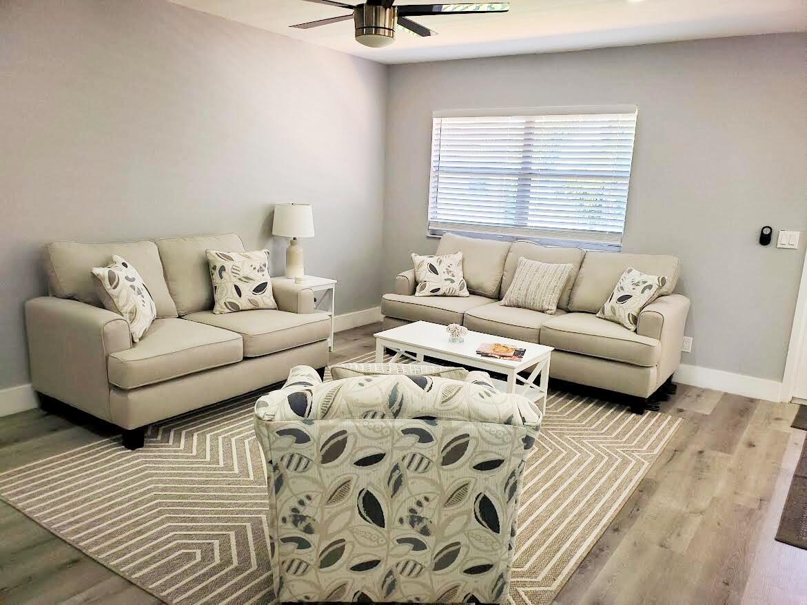 A living room features light-colored sofas, a patterned armchair, and a geometric area rug — 564 Saxony L Drive # 564, Delray Beach FL 33446, DELRAY BEACH, FL