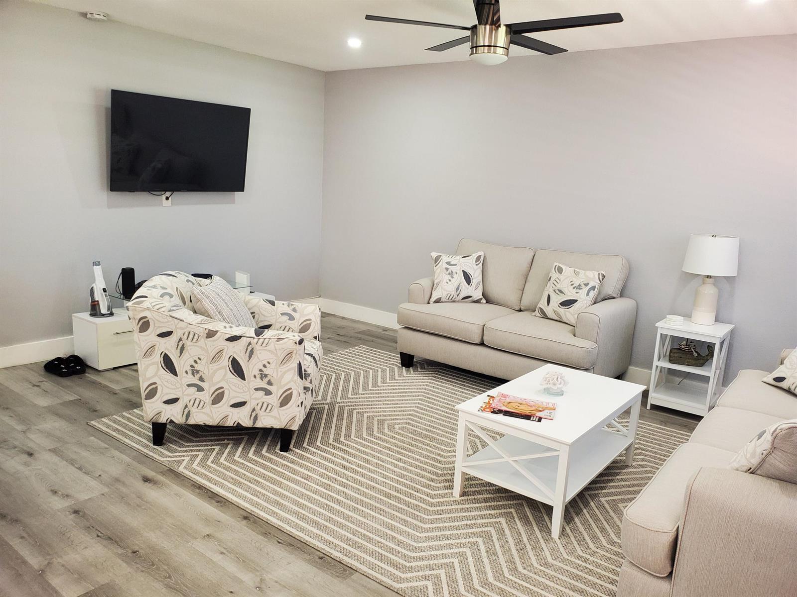 A living room features light gray walls, wood-look flooring, a patterned rug, and neutral furniture — 564 Saxony L Drive # 564, Delray Beach FL 33446, DELRAY BEACH, FL