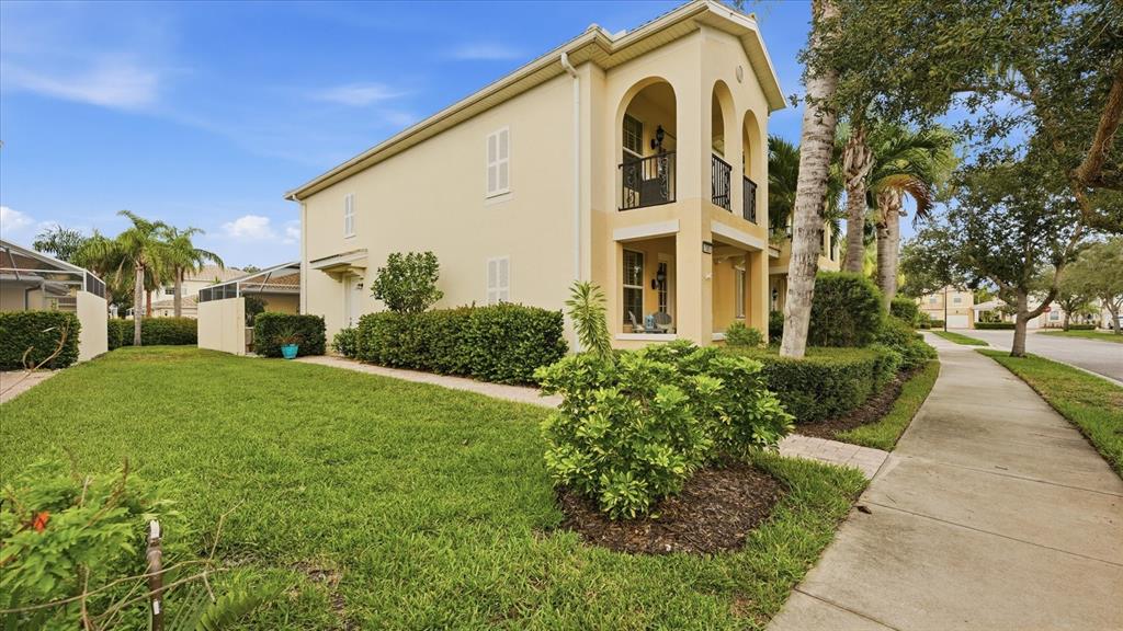A two-story yellow stucco building with arched balconies and a landscaped lawn — 1585 DORGALI DRIVE, SARASOTA, FL