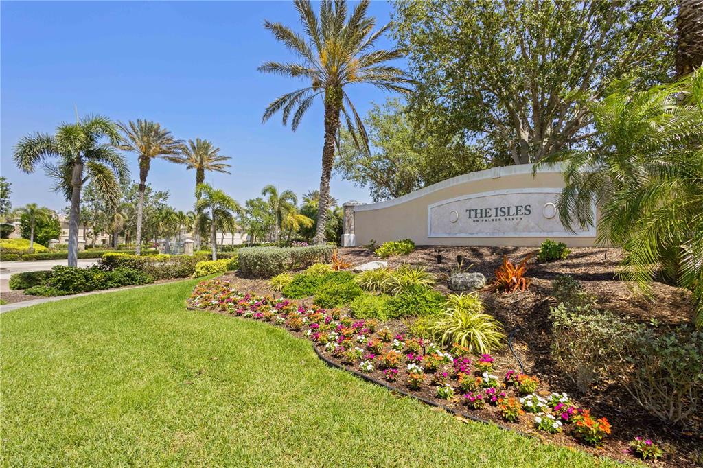 A landscaped entrance sign for The Isles on Palmer Ranch features palm trees and flowers — 1585 DORGALI DRIVE, SARASOTA, FL