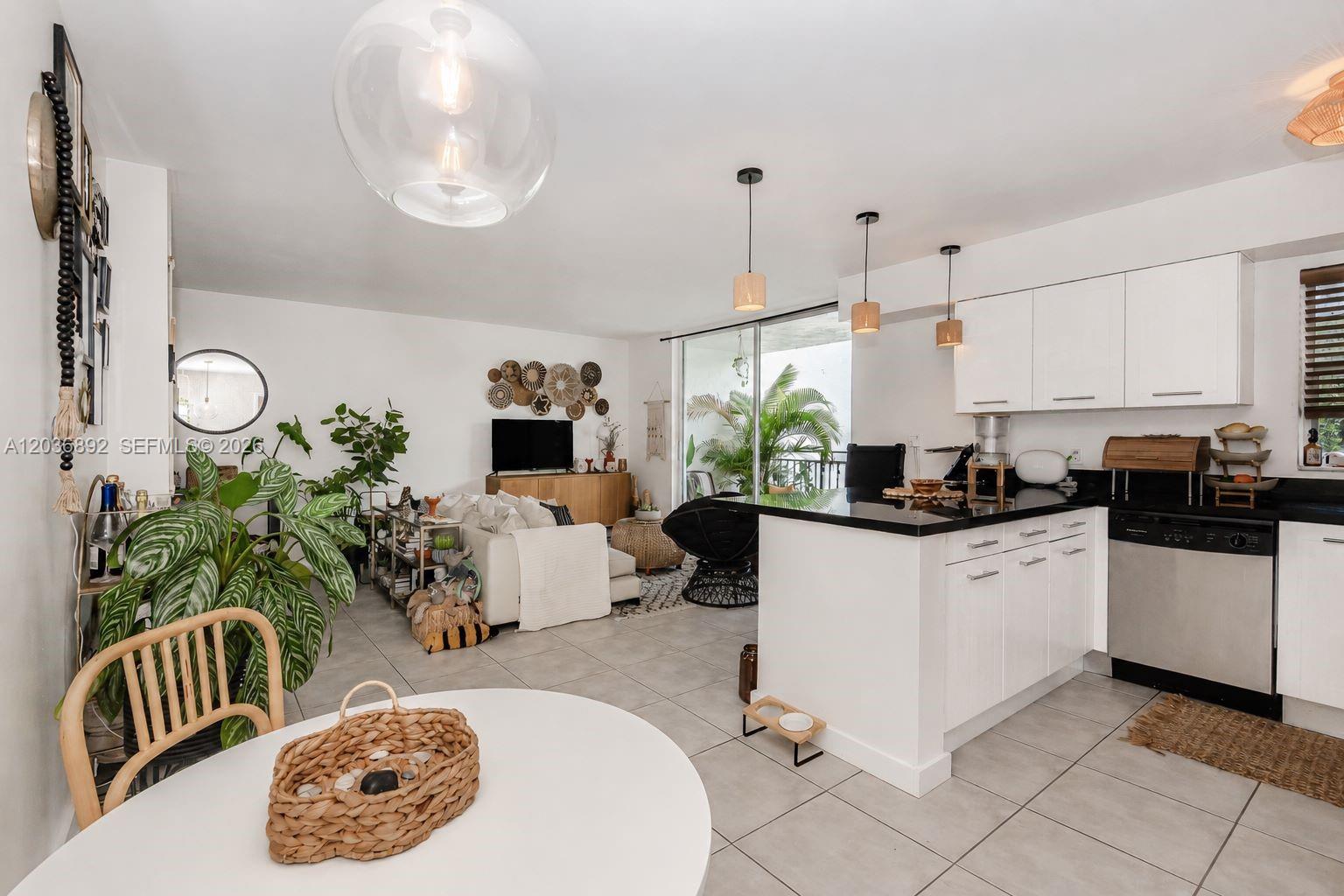 A bright open-concept living area features a kitchen with white cabinets and black countertops — 777 NE 62nd St # C302, Miami FL 33138, MIAMI, FL