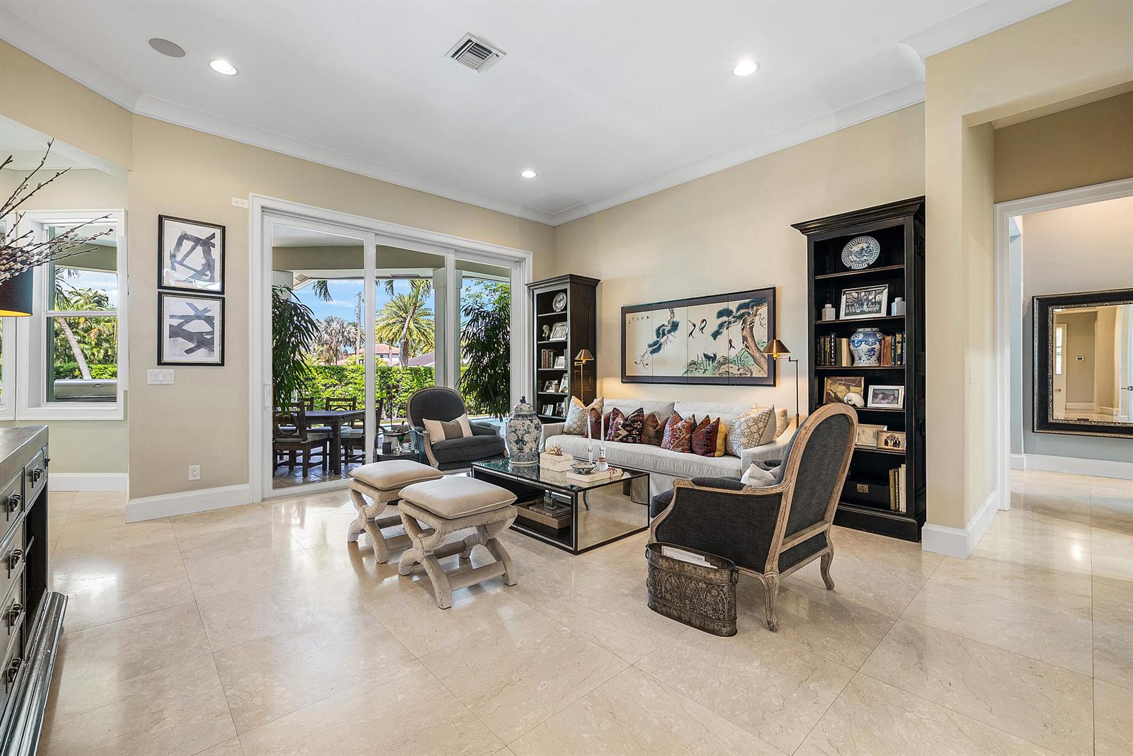 A living room features light tile floors, a sofa, armchairs, bookshelves, and sliding glass doors — 33 Spanish River Drive, Ocean Ridge FL 33435, OCEAN RIDGE, FL