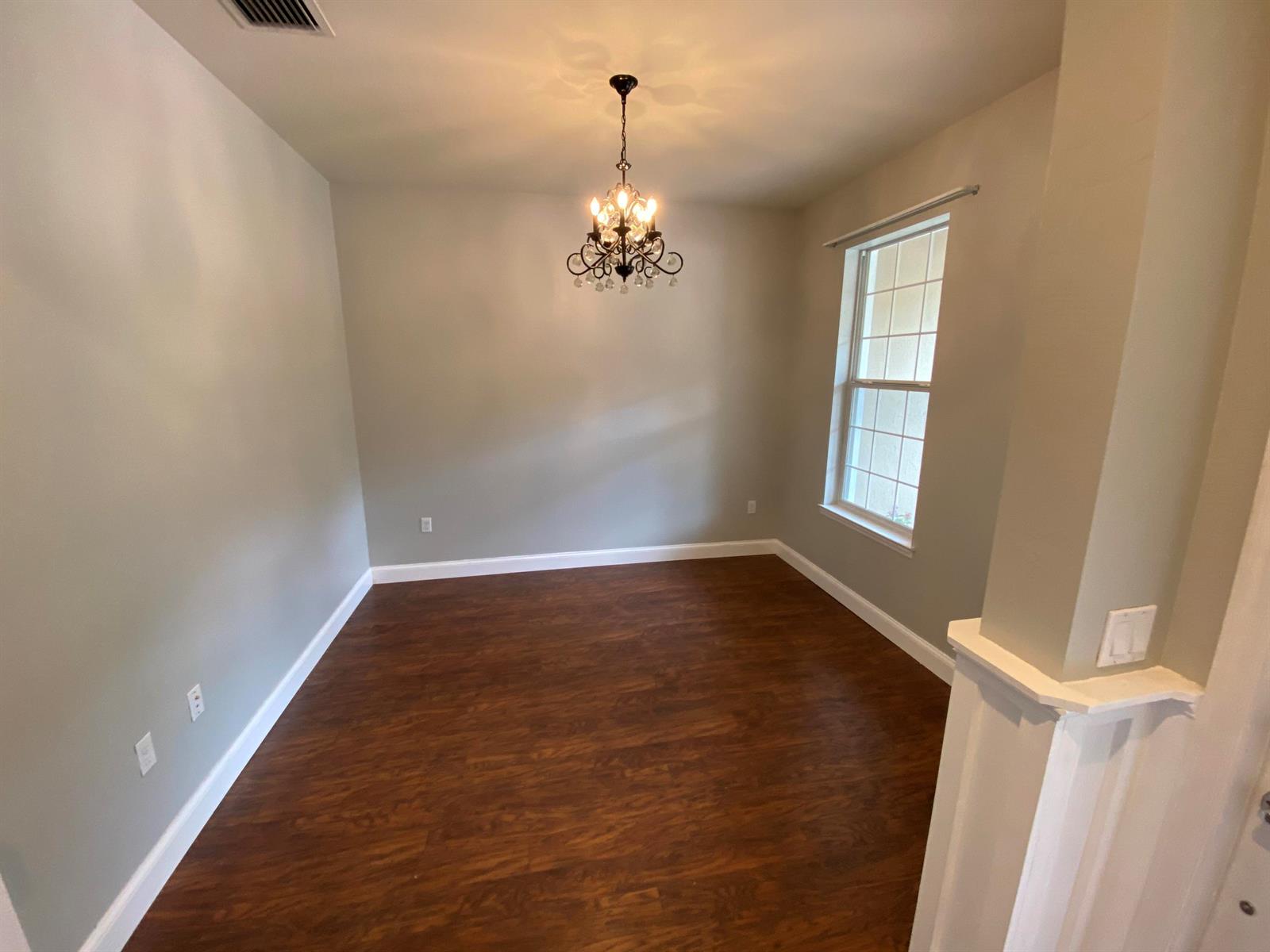 An empty dining room features dark wood flooring, light gray walls, and a crystal chandelier — 9238 Wrangler Drive # L, Wellington FL 33467, WELLINGTON, FL