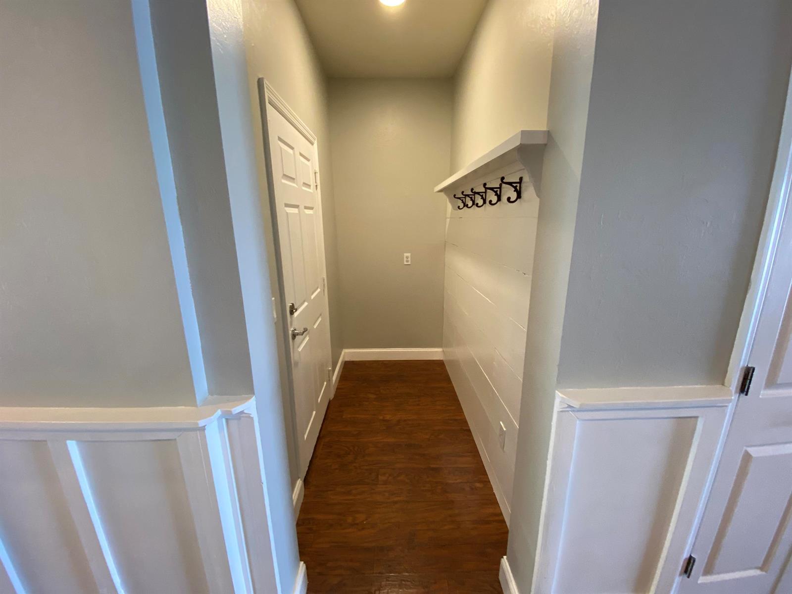 A narrow entryway features wood-look flooring, white shiplap walls with coat hooks, and a door — 9238 Wrangler Drive # L, Wellington FL 33467, WELLINGTON, FL