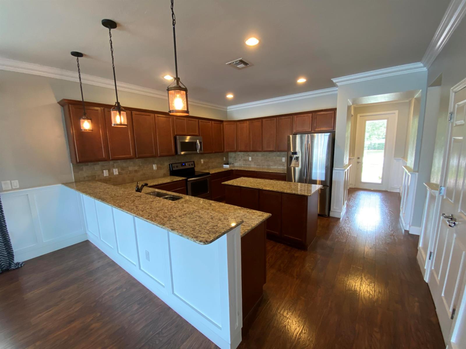A kitchen features dark wood cabinets, granite countertops, a center island, and hardwood flooring — 9238 Wrangler Drive # L, Wellington FL 33467, WELLINGTON, FL