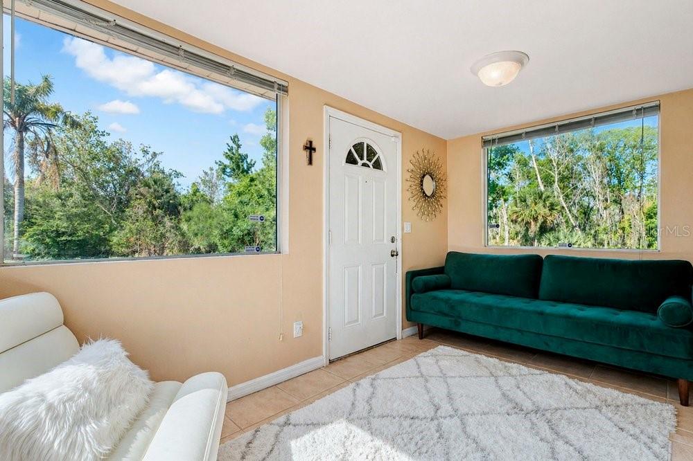 A sunroom features tile floors, a white door, a green sofa, and large windows — 595 3RD STREET, OVIEDO, FL