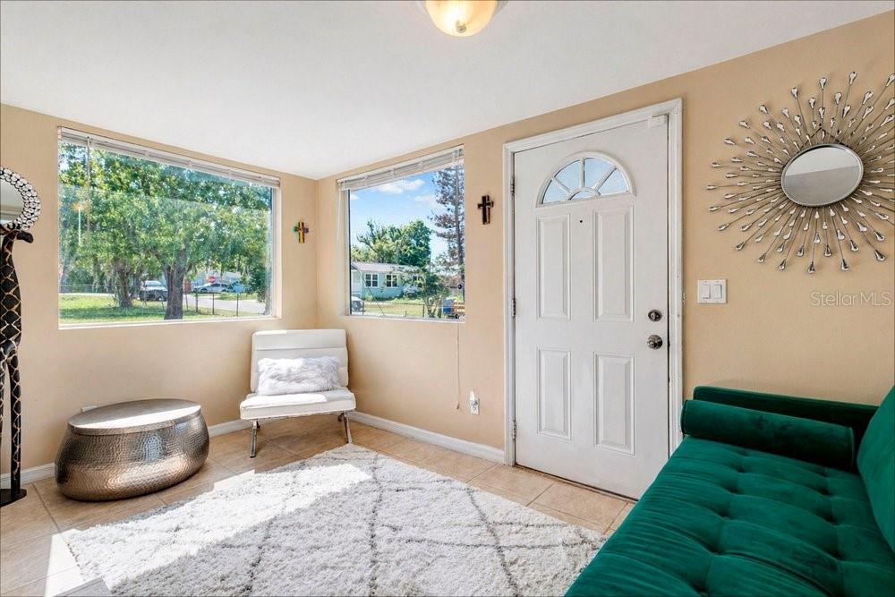 A bright living room features a white door, green sofa, white chair, and large windows — 595 3RD STREET, OVIEDO, FL