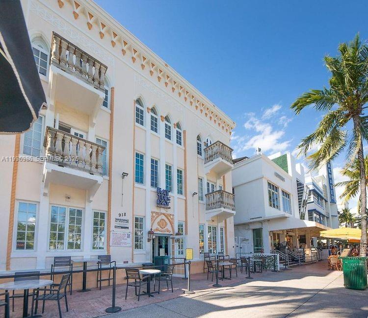 A multi-story building with balconies and outdoor seating sits along a sunny sidewalk — 918 Ocean Dr # 203, Miami Beach FL 33139, MIAMI BEACH, FL