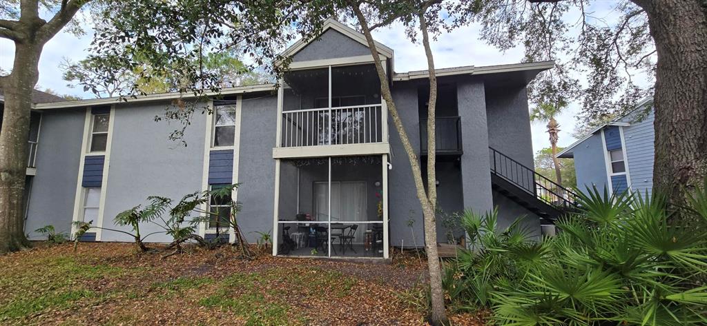 The exterior of a two-story apartment building features gray stucco walls and screened-in balconies — 3831 NAUTICAL WAY UNIT 203, KISSIMMEE, FL
