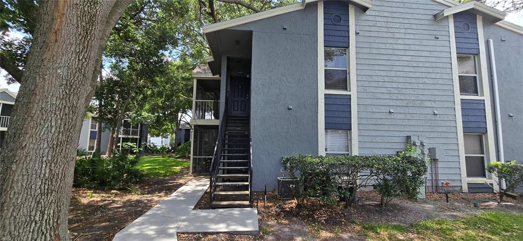 A two-story apartment building exterior features gray siding, dark blue accents, and an outdoor staircase — 3831 NAUTICAL WAY UNIT 203, KISSIMMEE, FL