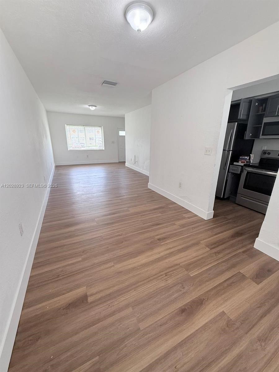 This room features light wood-look flooring, white walls, and an adjacent kitchen area — 209 NW 84th St # 209, Miami FL 33150, MIAMI, FL