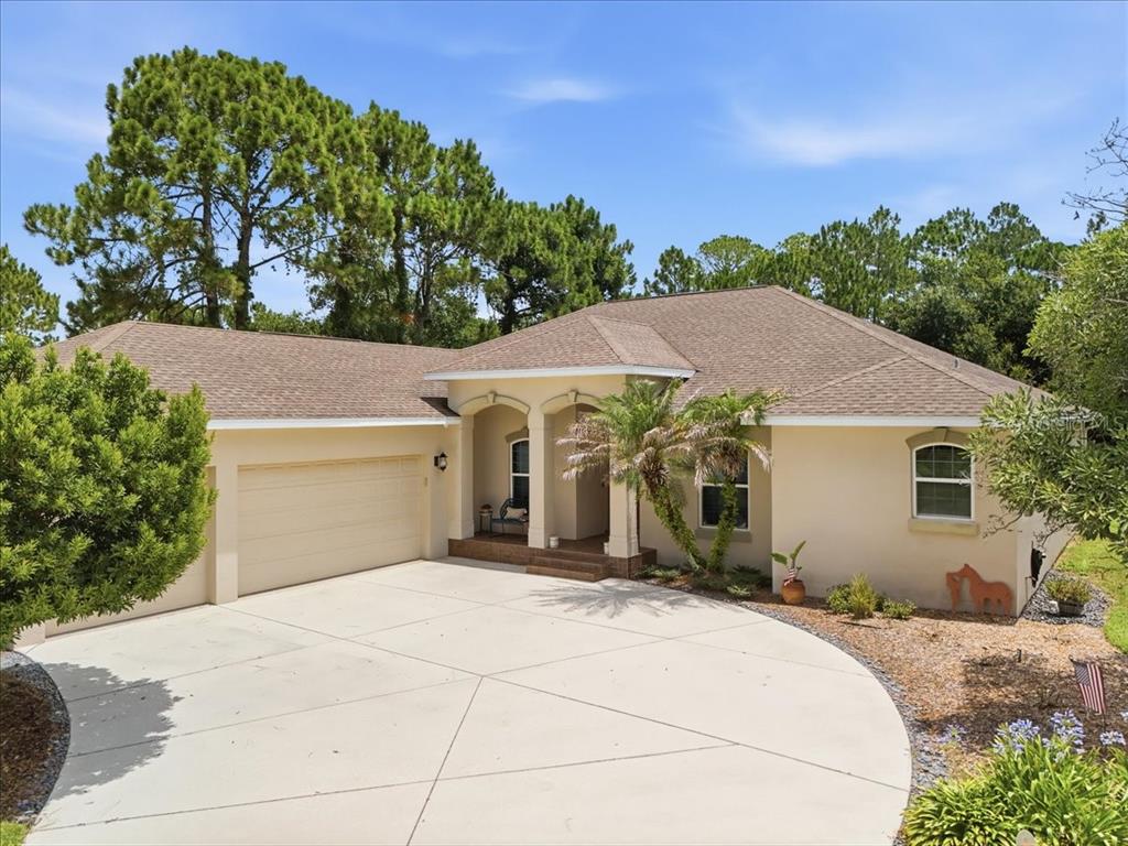 A single-story house with a beige stucco exterior, a two-car garage, and a concrete driveway — 3095 FAWN LAKE BOULEVARD, MIMS, FL