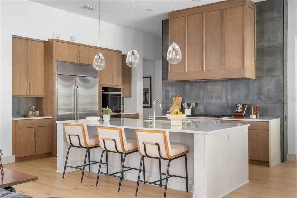 A modern kitchen features light wood cabinets, a white island with bar stools, and dark tile — TBD NW 150TH BOULEVARD, NEWBERRY, FL
