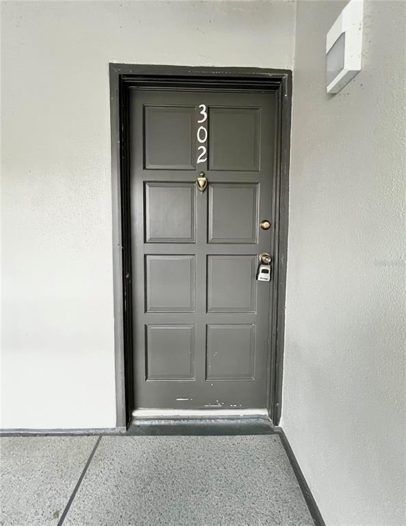 A dark gray front door with the number 302 is set in a light gray wall — 2650 COUNTRYSIDE BOULEVARD UNIT B302, CLEARWATER, FL