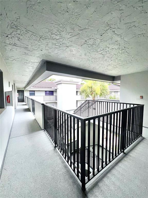 An outdoor apartment building walkway features a black metal railing overlooking a stairwell — 2650 COUNTRYSIDE BOULEVARD UNIT B302, CLEARWATER, FL