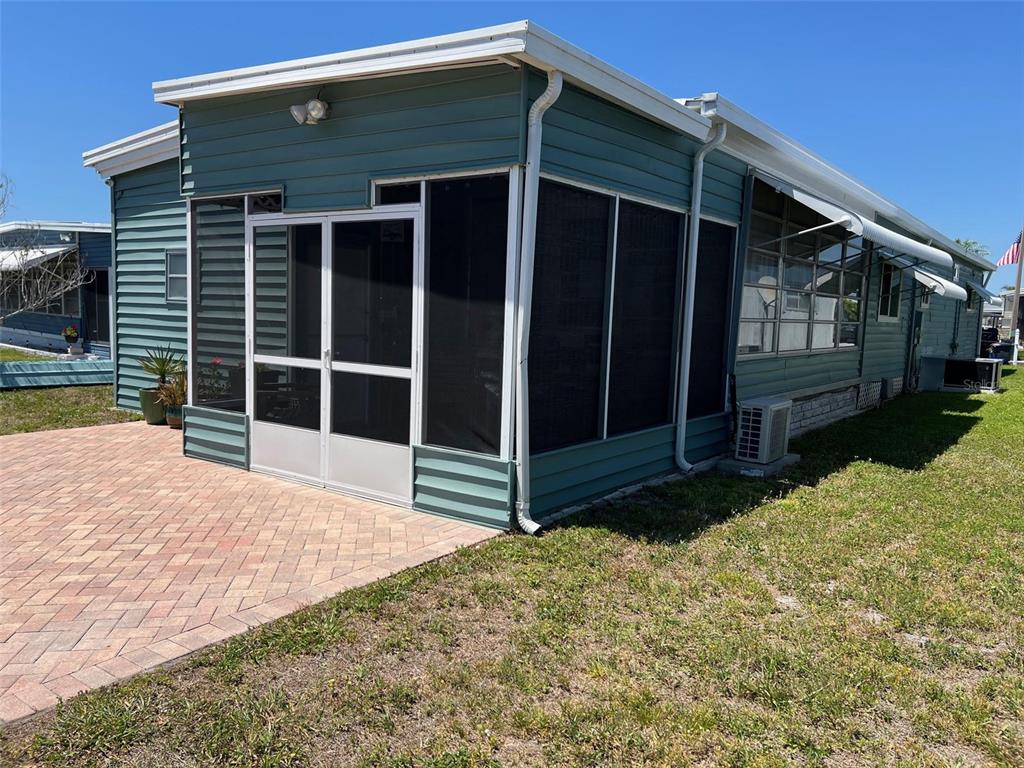 A teal mobile home with a screened-in porch and a brick paver patio — 13225 101ST STREET UNIT 356, LARGO, FL