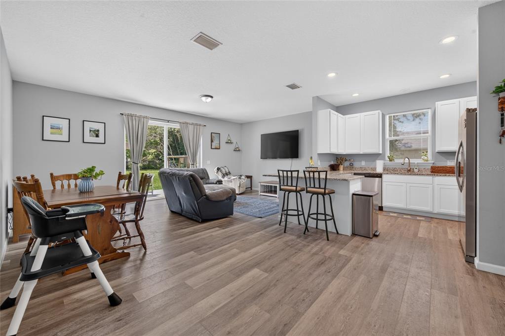 An open-concept living area features a kitchen with white cabinets, a dining space, and flooring — 1462 5TH AVENUE, DELAND, FL