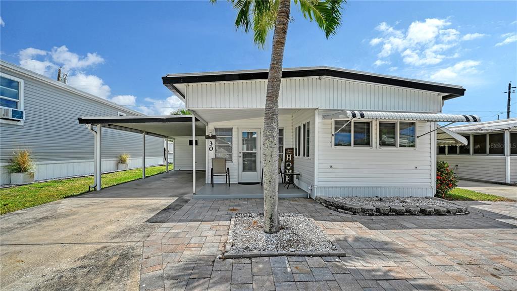 A white mobile home with a carport, a front porch, and a paved brick driveway — 10315 CORTEZ ROAD W UNIT 30-5, BRADENTON, FL
