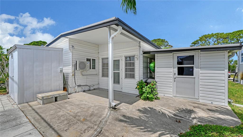 A white-sided house exterior features a concrete patio, a covered porch, and a storage shed — 10315 CORTEZ ROAD W UNIT 30-5, BRADENTON, FL