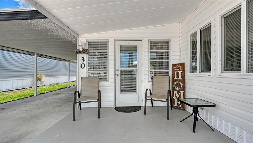 A covered porch features two chairs, a small table, and a welcome sign by the door — 10315 CORTEZ ROAD W UNIT 30-5, BRADENTON, FL