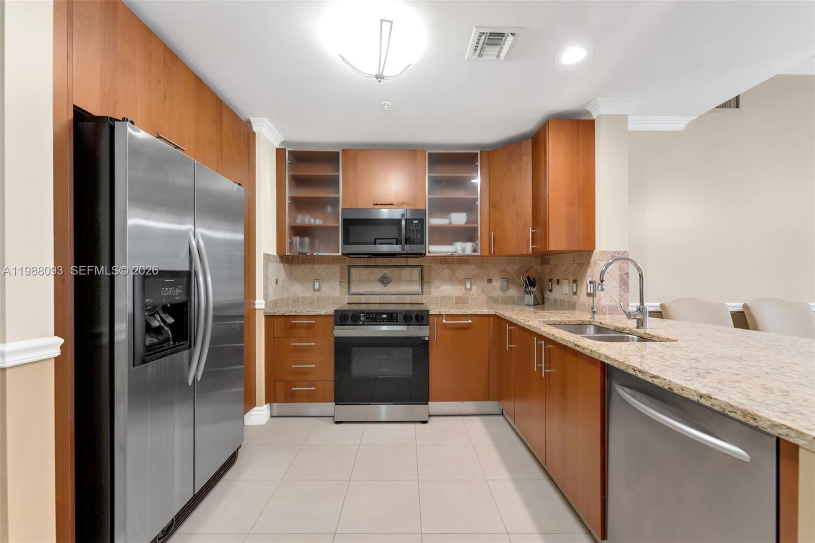 A kitchen features stainless steel appliances, wood cabinetry, and granite countertops — 1945 S Ocean Dr # 604, Hallandale Beach FL 33009, HALLANDALE BEACH, FL