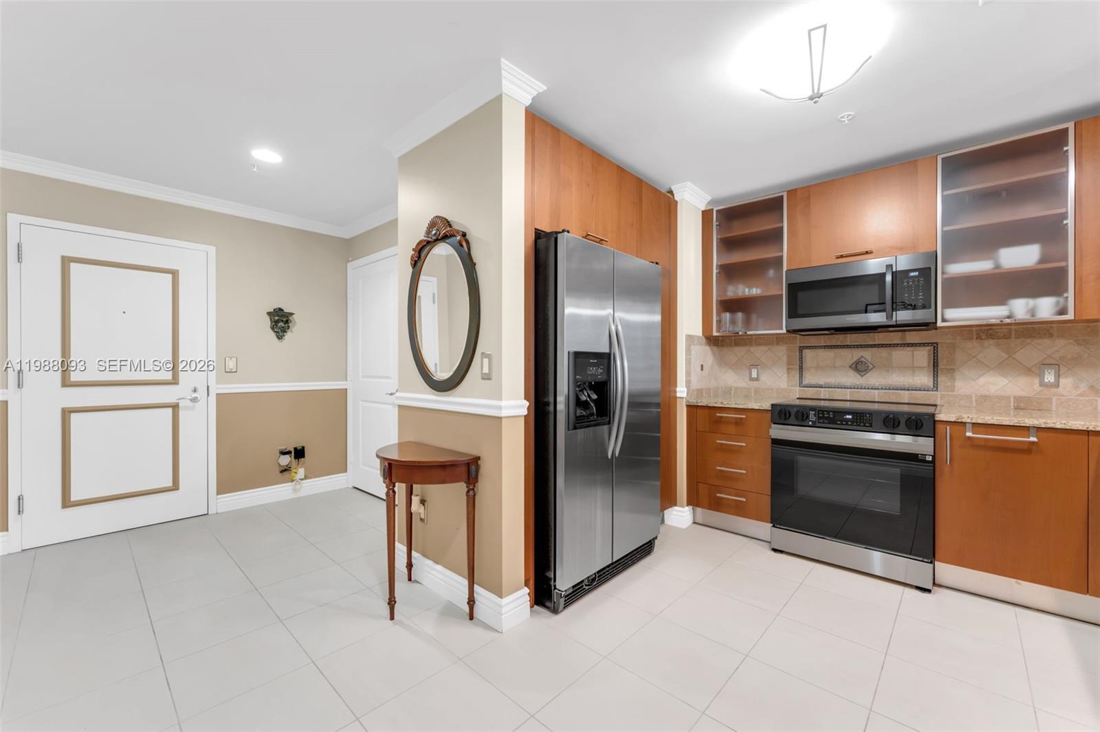 A kitchen features stainless steel appliances, wood cabinets, and a small console table with mirror — 1945 S Ocean Dr # 604, Hallandale Beach FL 33009, HALLANDALE BEACH, FL