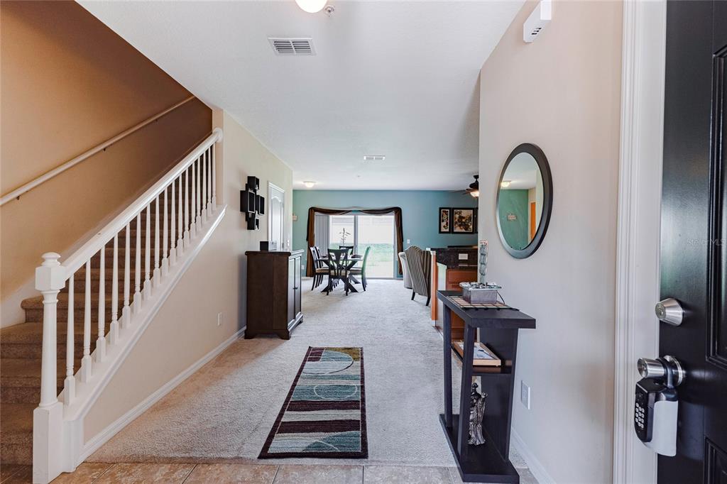 An entryway leads into a carpeted living area with a staircase and dining space — 1921 CHATHAM PLACE DRIVE, ORLANDO, FL