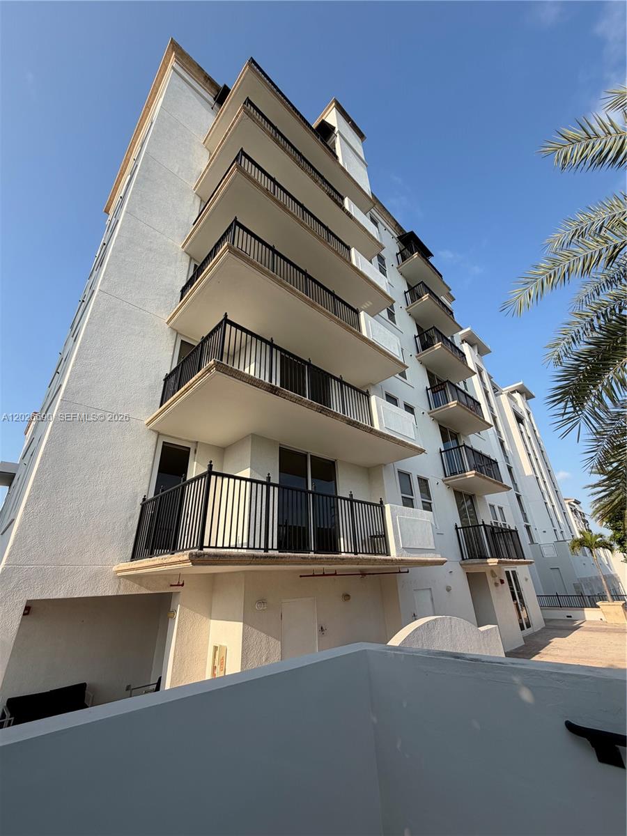 A low-angle view of a multi-story white apartment building with stacked balconies and black railings — 4100 Salzedo St # 508, Coral Gables FL 33146, CORAL GABLES, FL