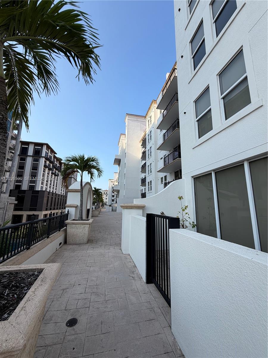 A paved outdoor walkway runs between a white multi-story building and a dark apartment complex — 4100 Salzedo St # 508, Coral Gables FL 33146, CORAL GABLES, FL