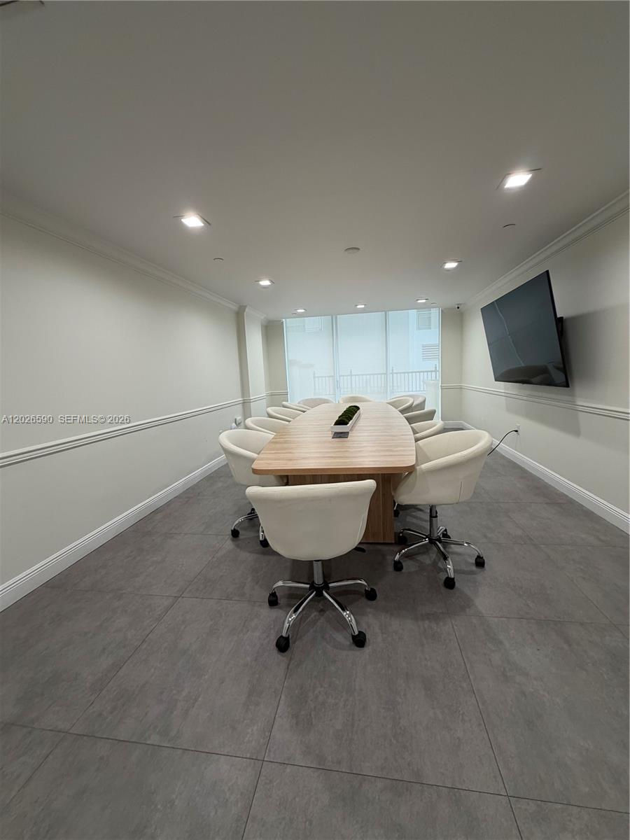 A living room features a grey sofa, a wall-mounted television, and tile flooring — 4100 Salzedo St # 508, Coral Gables FL 33146, CORAL GABLES, FL