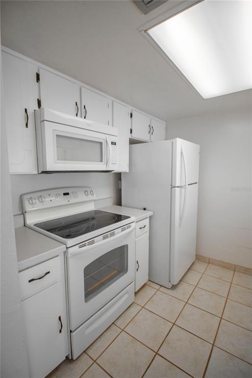 A kitchen features white cabinets, a white electric range, a microwave, and a white refrigerator — 3600 S OCEAN SHORE BOULEVARD UNIT 115, FLAGLER BEACH, FL