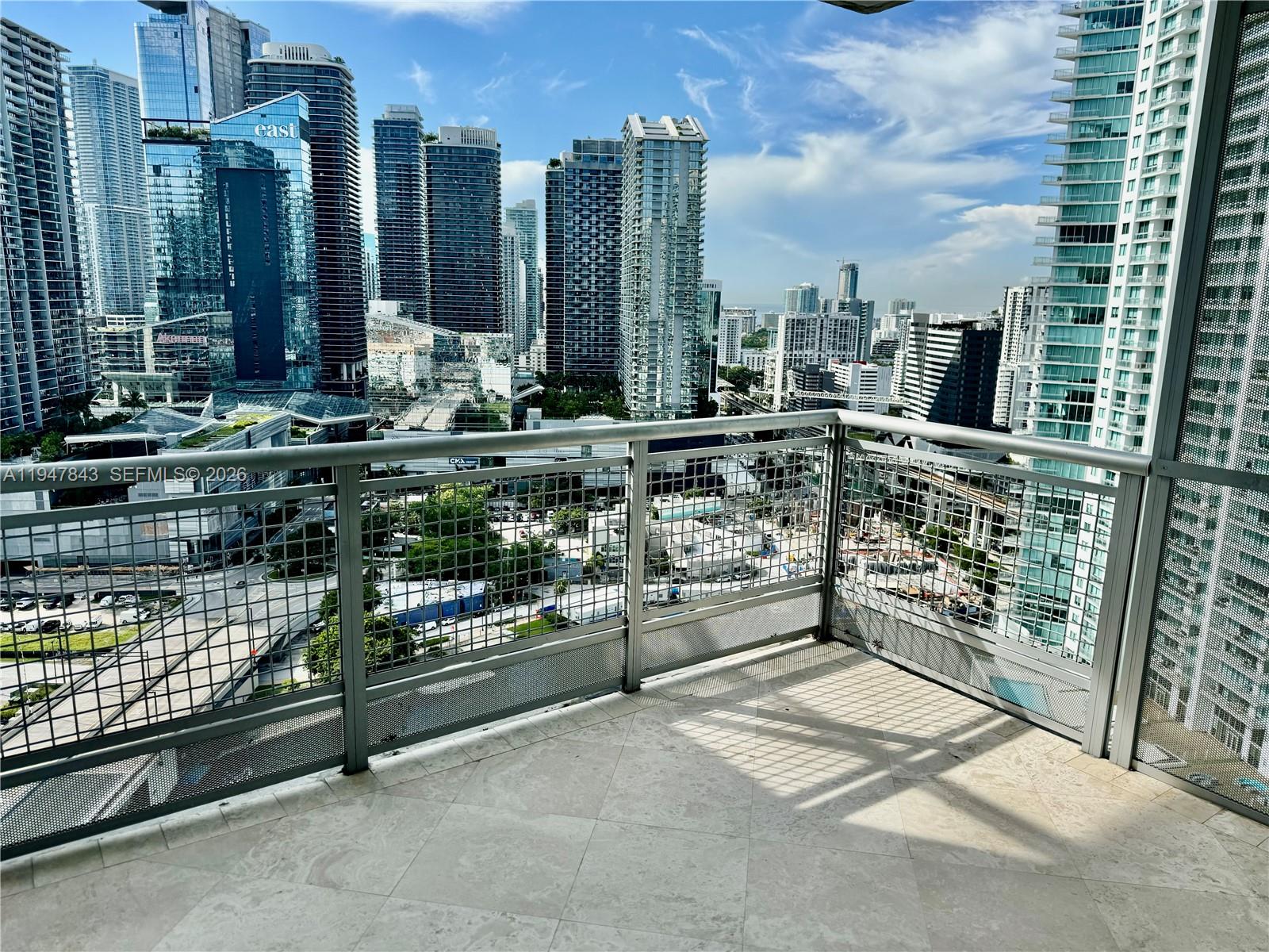 A high-rise balcony with metal railings overlooks a dense urban skyline of glass skyscrapers — 350 S Miami Ave # 3008, Miami FL 33130, MIAMI, FL