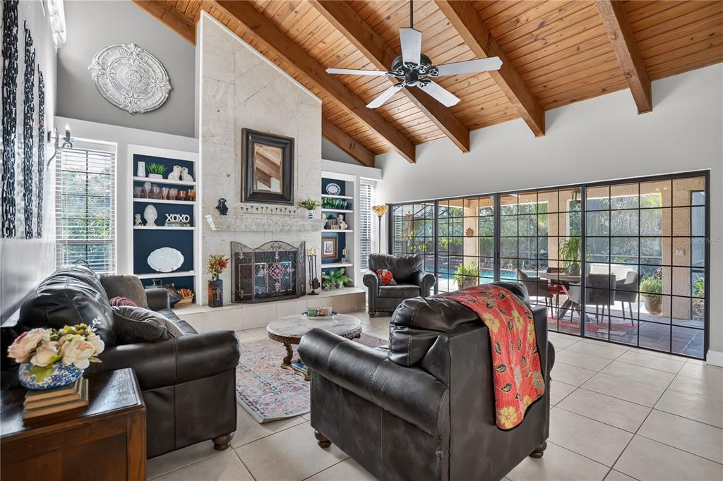A living room features a stone fireplace, vaulted wood-beam ceiling, and large glass sliding doors — 1367 CAMPBELL STREET, ORLANDO, FL