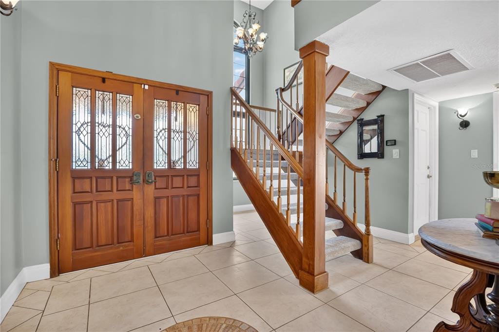 A dining room features a wooden table, chairs, bench, chandelier, and green walls — 1367 CAMPBELL STREET, ORLANDO, FL