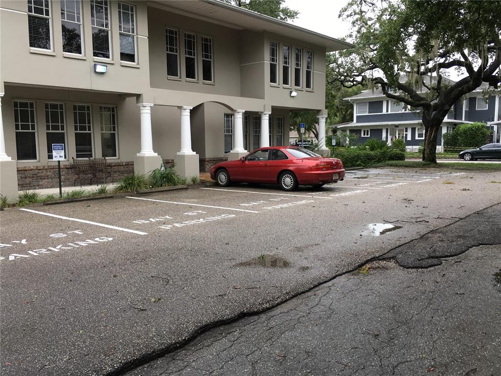 A red car is parked in a paved lot in front of a two-story building — 611 W BAY STREET, TAMPA, FL