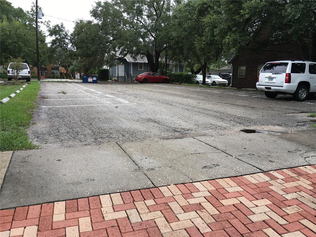 An outdoor parking lot with painted spaces, a dumpster, and several parked vehicles — 611 W BAY STREET, TAMPA, FL