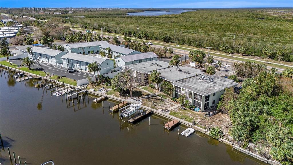 An aerial view shows a multi-story apartment complex situated along a canal with private docks — 10215 MANATEE AVENUE W UNIT 7, BRADENTON, FL