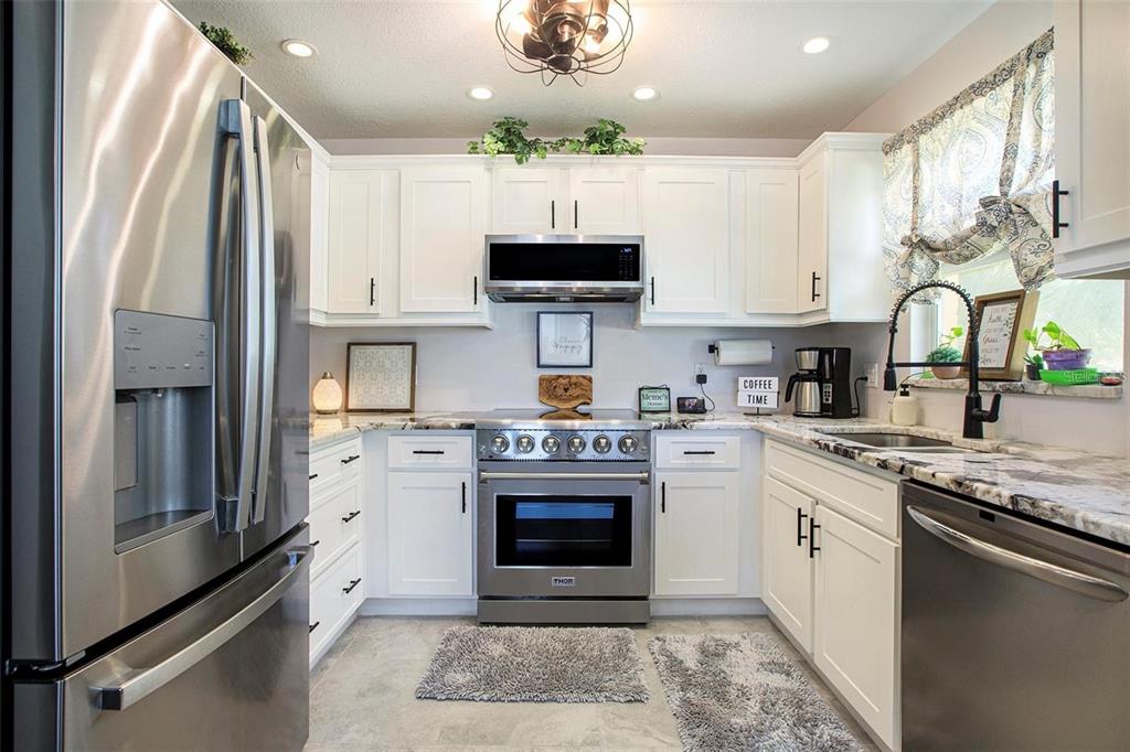 A kitchen with white cabinets, stainless steel appliances, and granite countertops — 10215 MANATEE AVENUE W UNIT 7, BRADENTON, FL