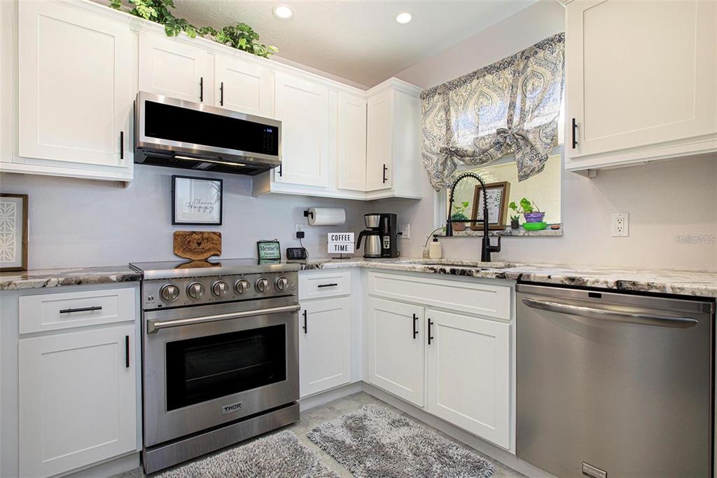 A kitchen features white cabinets, stainless steel appliances, and granite countertops — 10215 MANATEE AVENUE W UNIT 7, BRADENTON, FL
