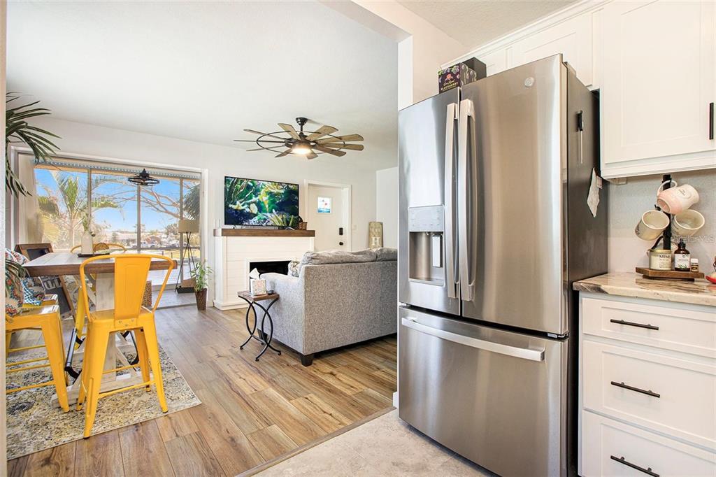 A kitchen with stainless steel appliances opens into a living room with a fireplace — 10215 MANATEE AVENUE W UNIT 7, BRADENTON, FL
