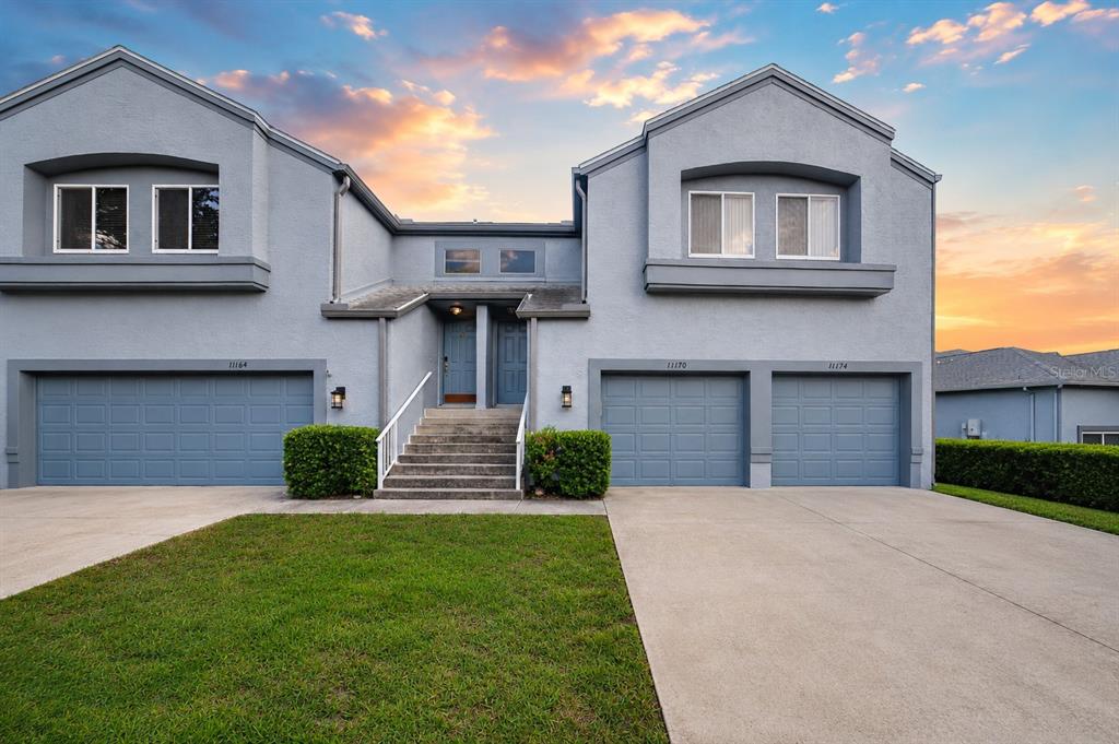A two-story gray stucco multi-family building with three garage doors and a central staircase — 11170 W COVE HARBOR DRIVE UNIT 121, CRYSTAL RIVER, FL