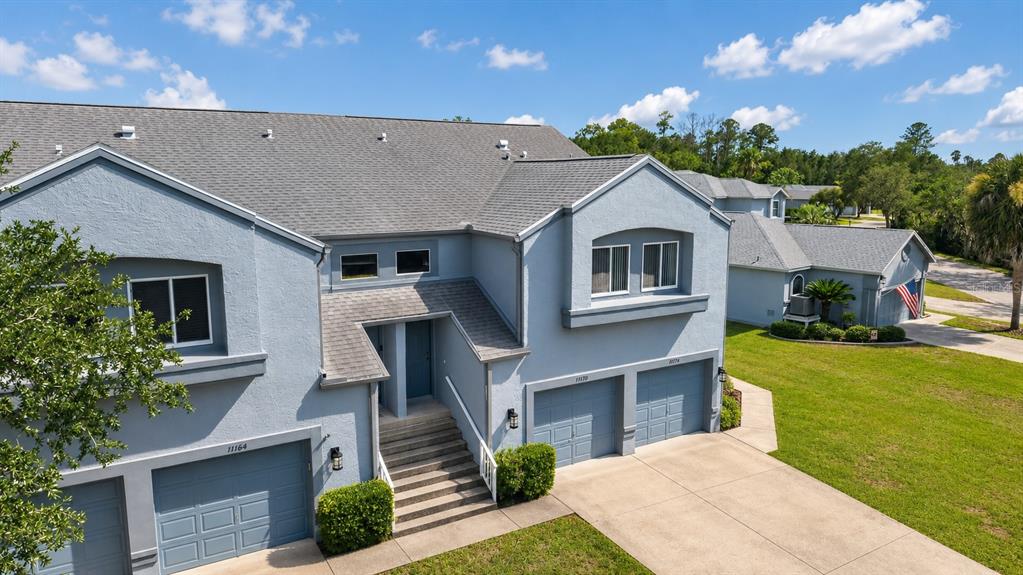 An exterior view of a multi-unit blue townhouse with gray shingled roofs and concrete driveways — 11170 W COVE HARBOR DRIVE UNIT 121, CRYSTAL RIVER, FL