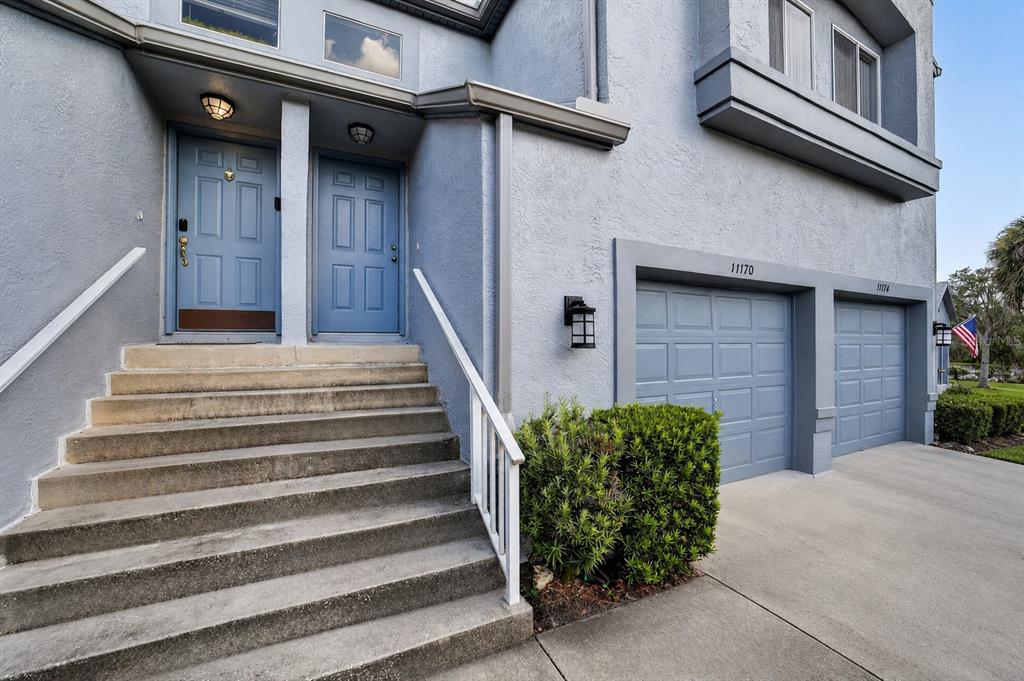 A blue townhouse exterior features a concrete staircase leading to two front doors and garages — 11170 W COVE HARBOR DRIVE UNIT 121, CRYSTAL RIVER, FL