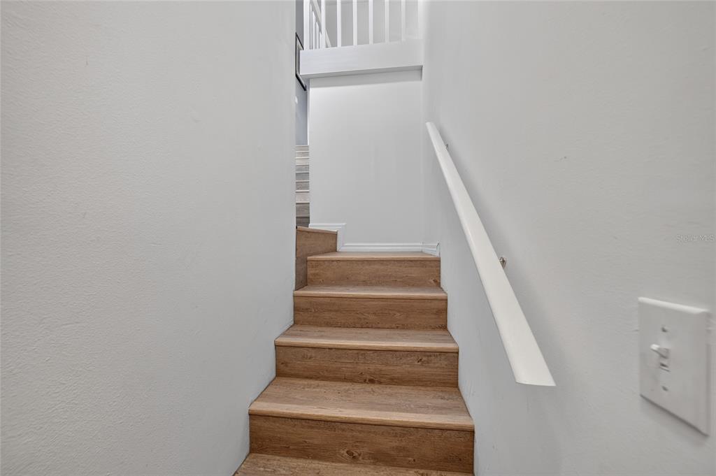 A wooden staircase with a white handrail leads upward between two plain gray walls — 11170 W COVE HARBOR DRIVE UNIT 121, CRYSTAL RIVER, FL