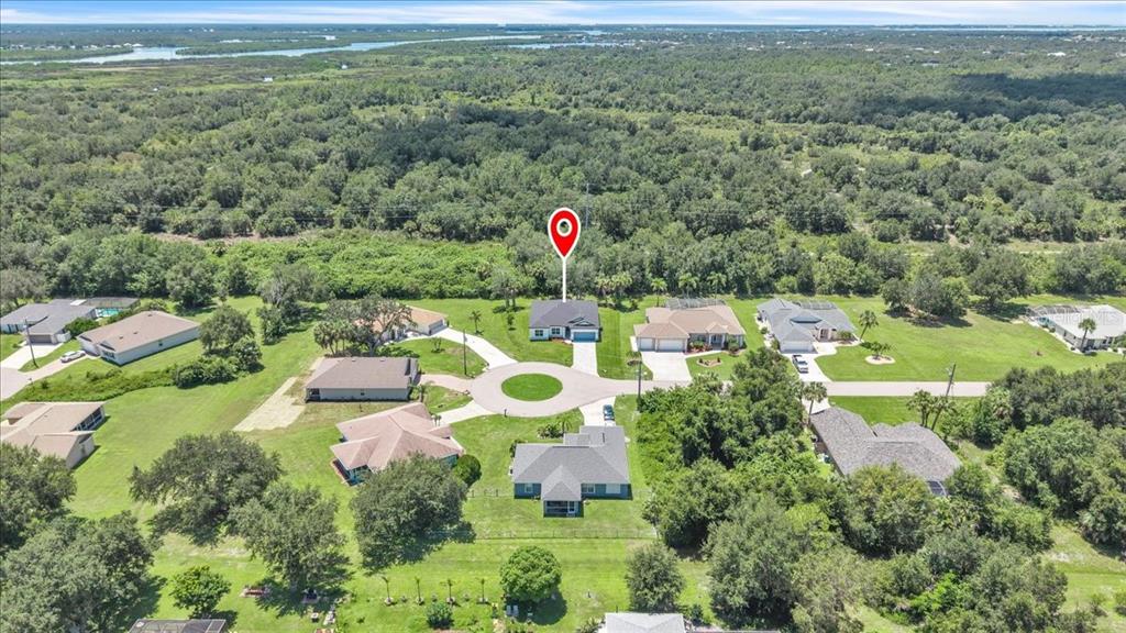 An aerial view shows a suburban cul-de-sac with several houses surrounded by dense green trees — 27431 NATAL DRIVE, PUNTA GORDA, FL