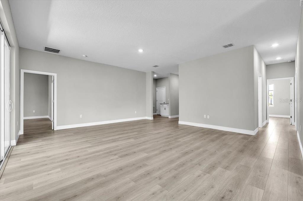 An empty room with light gray walls, wood-look flooring, and multiple doorways — 27431 NATAL DRIVE, PUNTA GORDA, FL