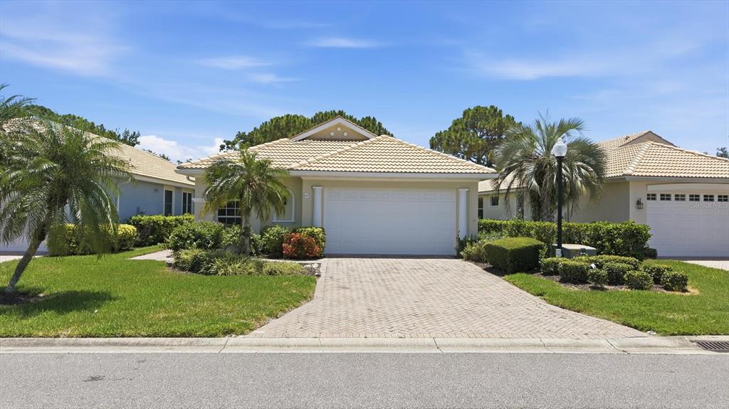 A single-story house with a beige exterior, a two-car garage, and a paved driveway — 4315 REFLECTIONS PARKWAY, SARASOTA, FL