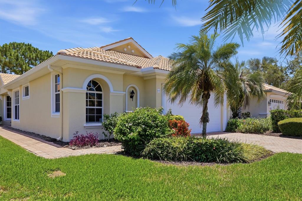 A single-story yellow house with a tile roof, palm tree, and paved driveway — 4315 REFLECTIONS PARKWAY, SARASOTA, FL